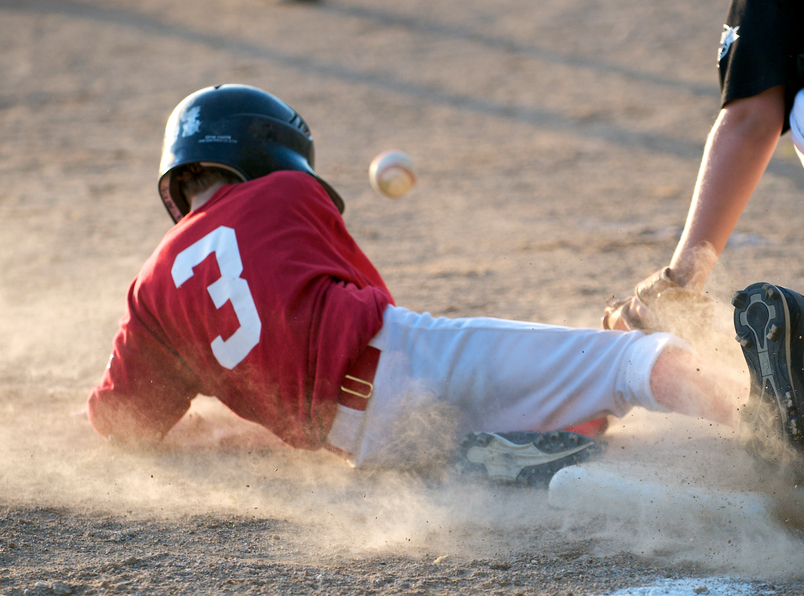 A kid sliding into a base playing baseball